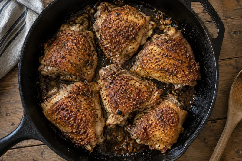 Bone-in chicken thighs with crisp browned skin in a cast iron skillet