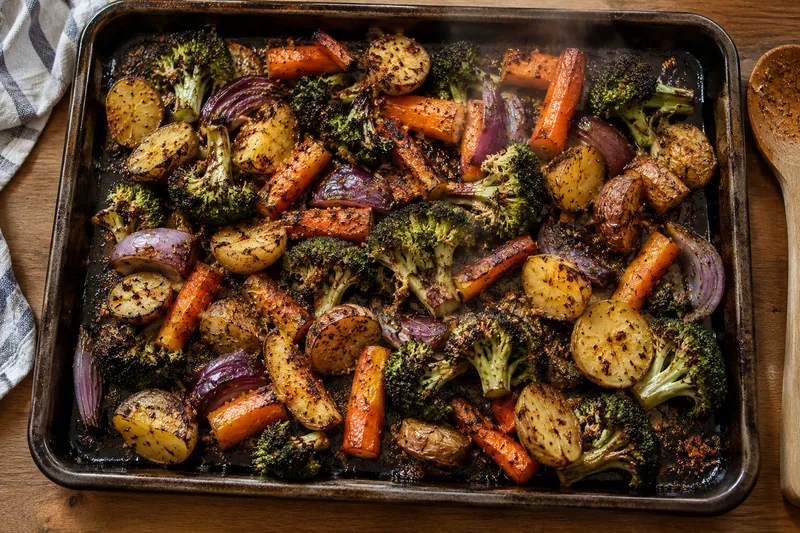 Roasted broccoli, carrots, potatoes and red onion on a sheet pan