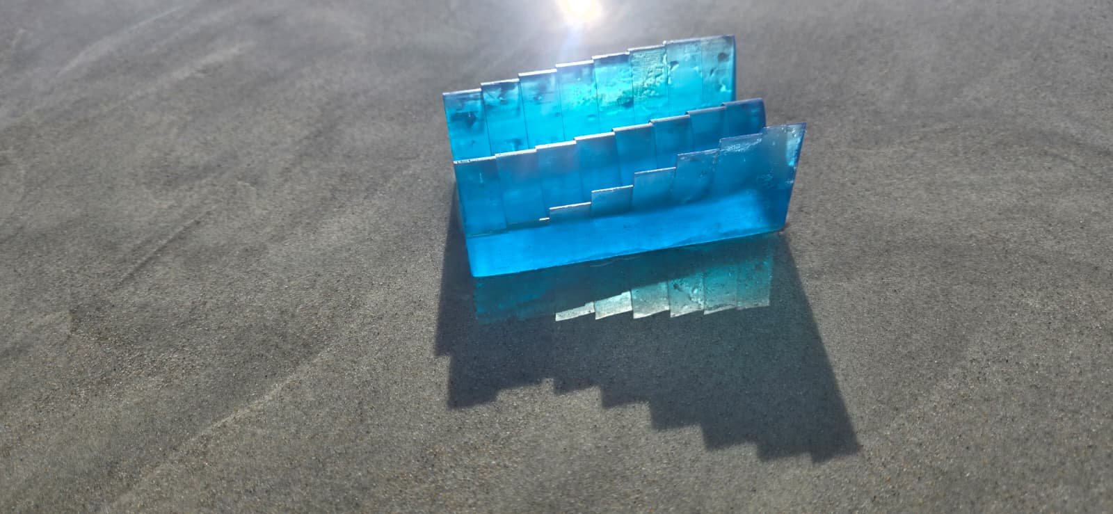 Blue resin tide keepsake casting a long shadow on the shoreline — wedding-weekend product example