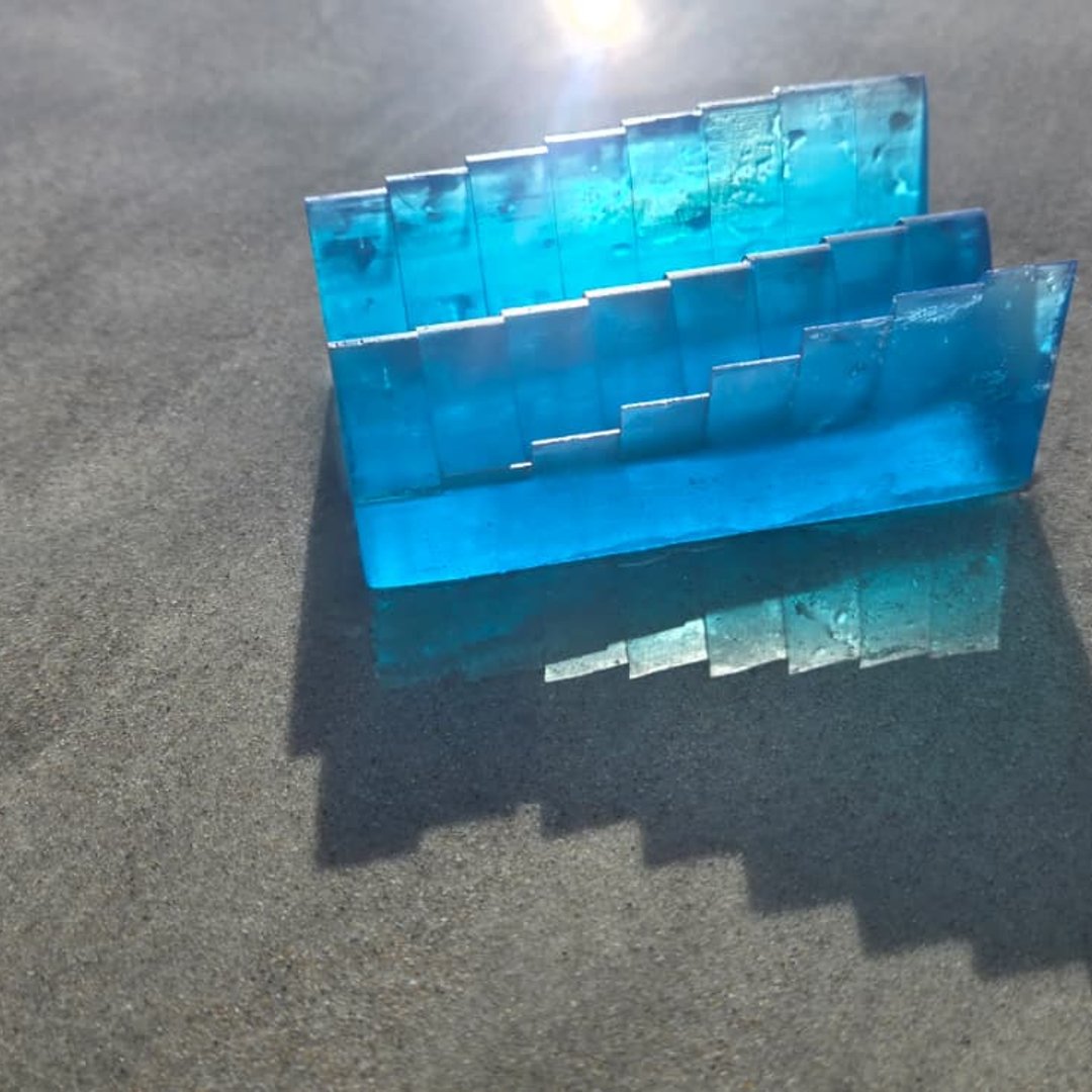 Blue tide-shaped resin keepsake casting a shadow on the shoreline