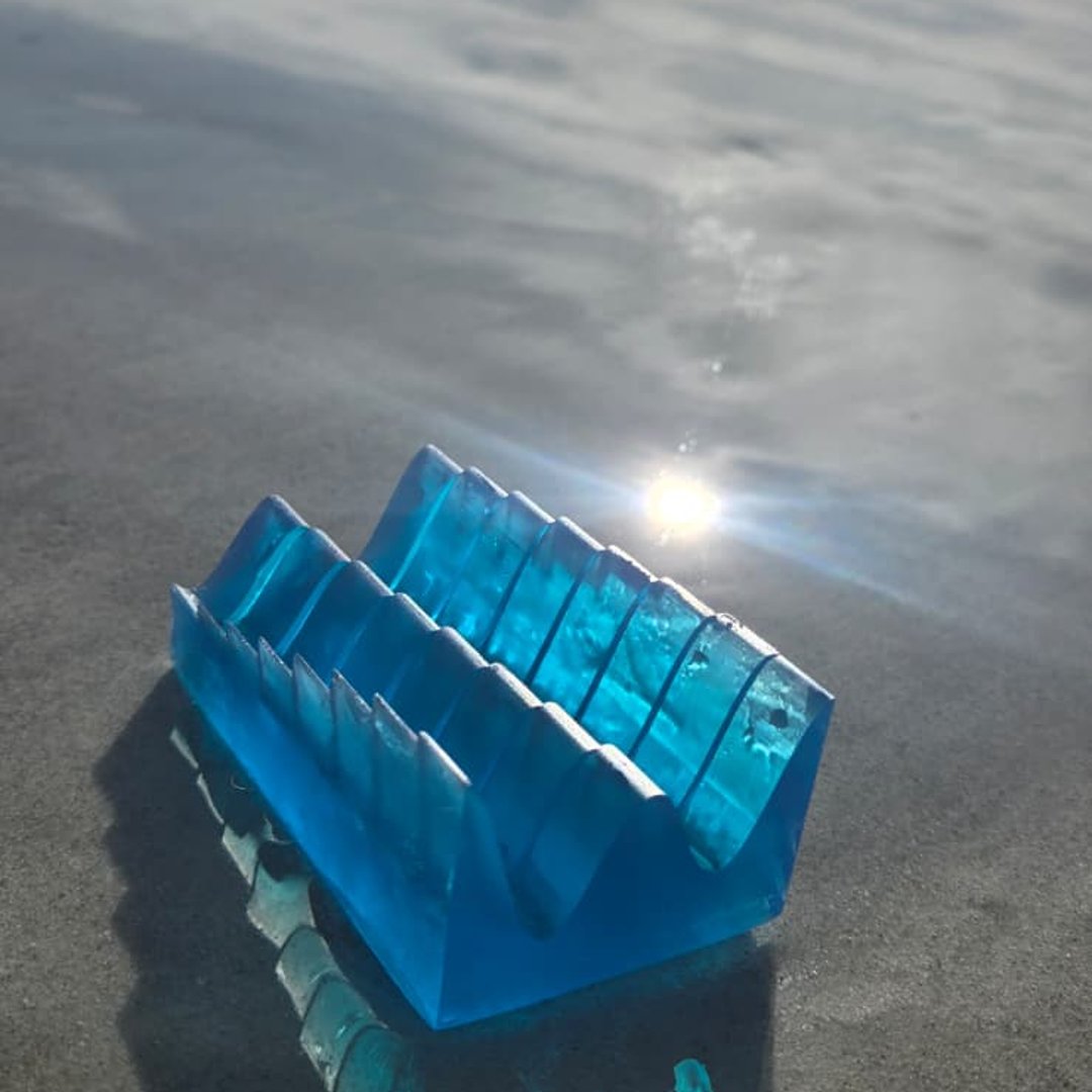 Translucent tide keepsake standing on wet sand, ocean behind