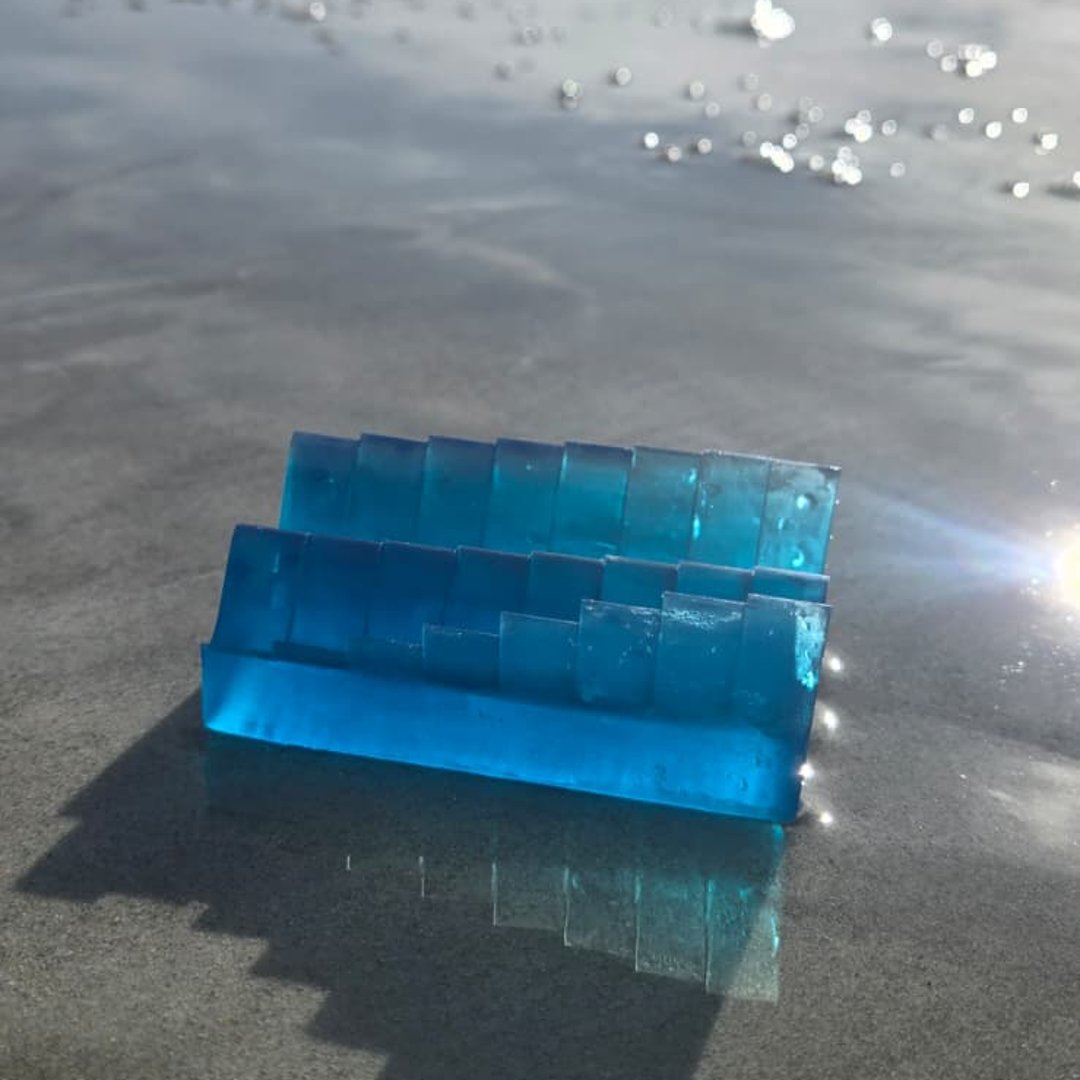 Two stacked tide-day layers of a blue resin keepsake on the sand