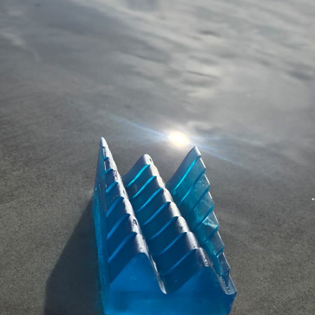 Profile of a blue resin tide keepsake on wet sand