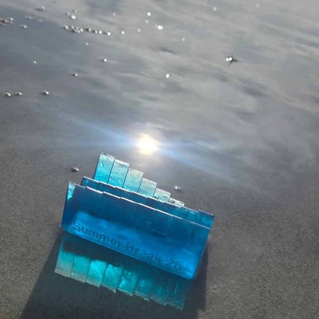 Tide-shaped resin keepsake catching the light on the sand